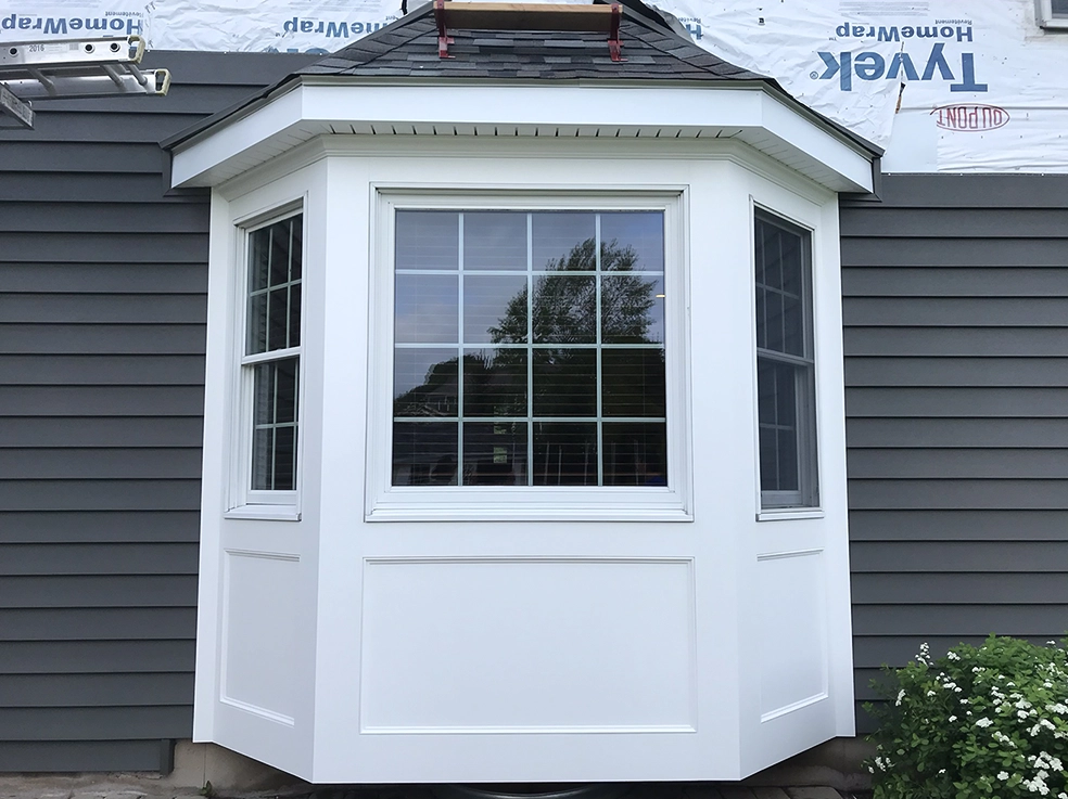 Bay window replacement on a house with gray siding replacement